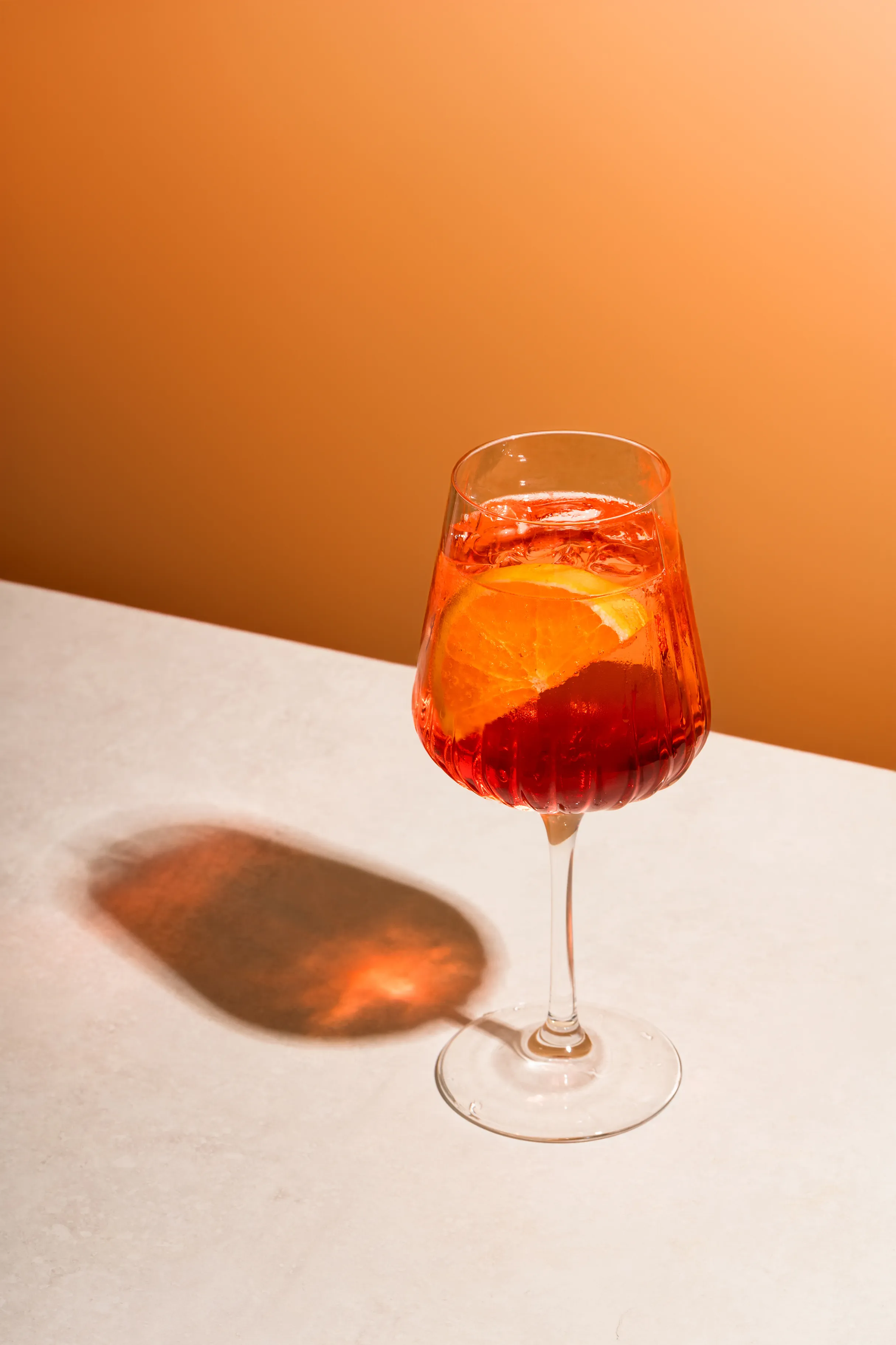 Aperol spritz tipo kokteilis oranžiniame fone
