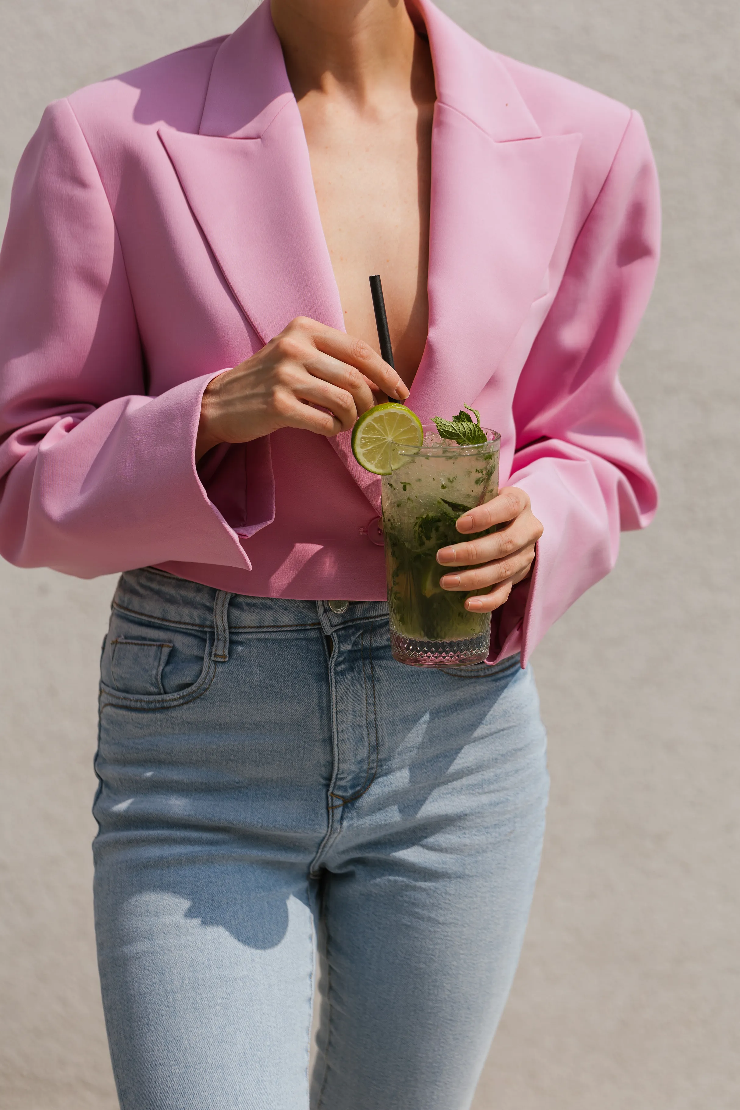 Moteris rožiniu švarku laiko mohito kokteilį