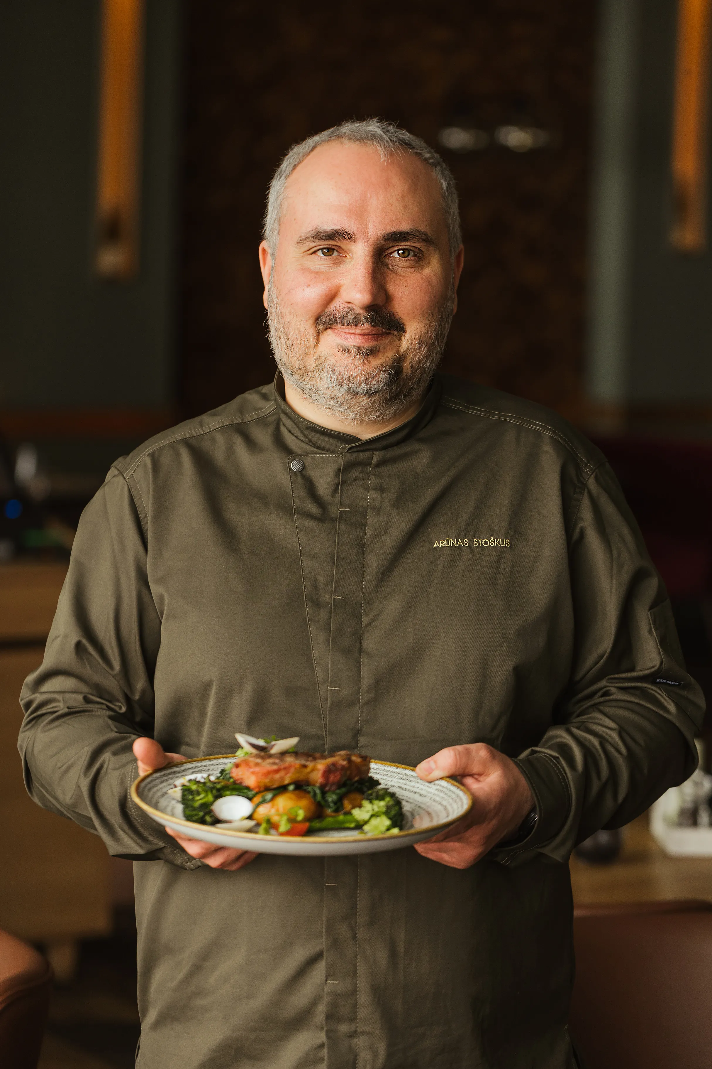 Šefas laiko lėkštę su patiekalu restorane